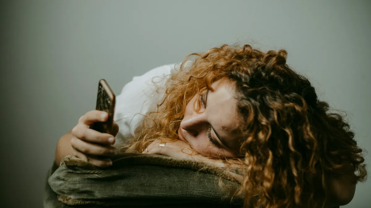 スマートフォンを握ったままクッションに頭を預ける女性